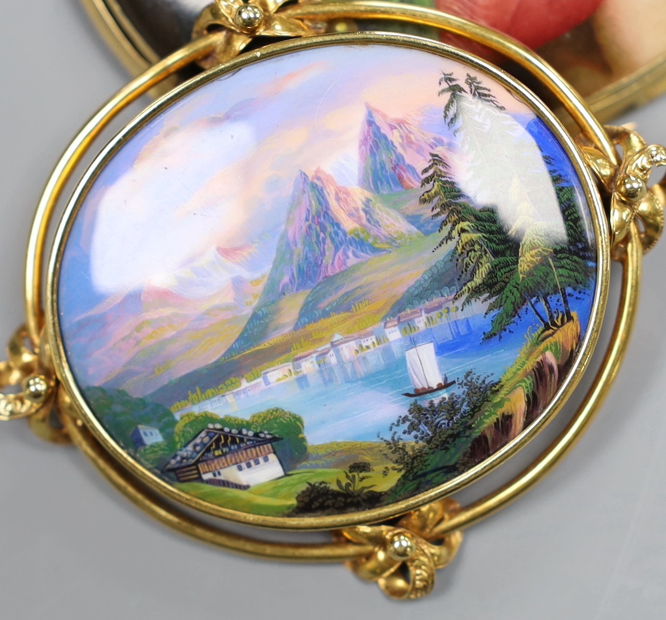 A Victorian 15ct gold mounted porcelain plaque, decorated with the Madonna della Sedia, 8cm, a Swiss landscape enamel brooch with 15ct mount, 6.5cm and a Pinchbeck brooch with turquoise set foliate decoration